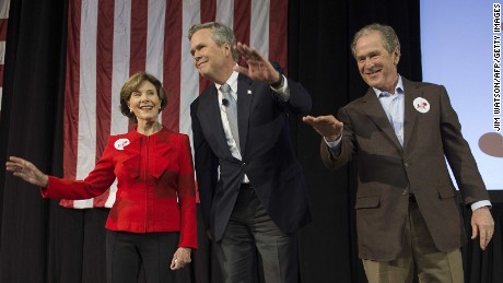 Former US President George W. Bush waves with his wife Laura as he stands with his brother and Republican presidential candidate Jeb Bush during a campaign rally in Charleston South Carolina