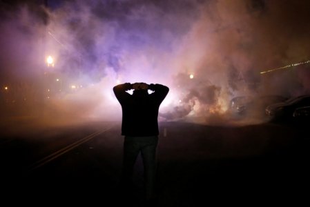 A protester stands with his hands on his head as a cloud of tear gas approaches after a grand jury returned no indictment in the shooting of Michael Brown in Ferguson Missouri in this