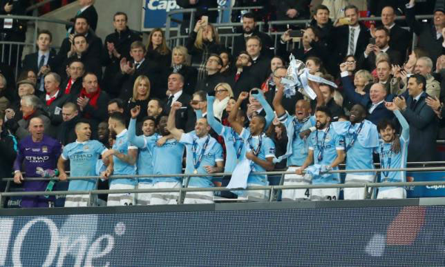 Manchester City's Vincent Kompany celebrates winning the Capital One Cup Final with the trophy and