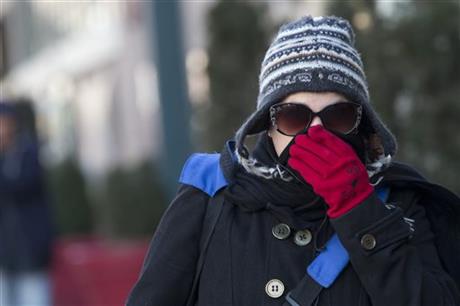 A woman lifts her scarf up in front of her nose to shield from the cold air Friday Feb. 12 2016 in New York. The National Weather Service predicts temperatures well below freezing on Saturday for New York. But wind chills could drop even lower and