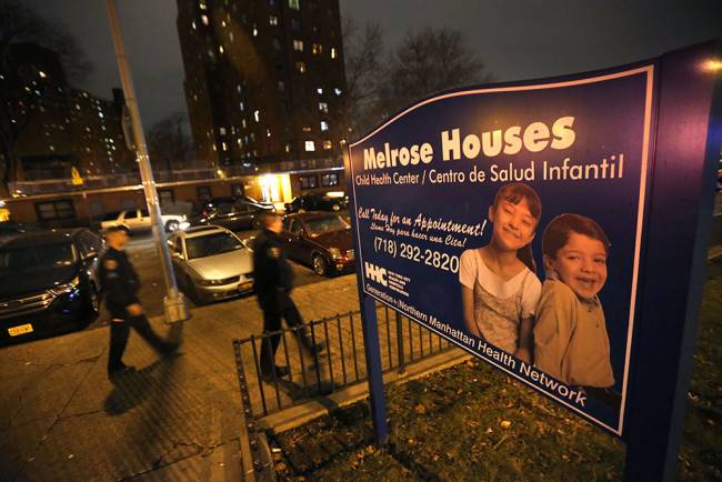 Police officers walk near the site where two police officers were shot at the Melrose Houses in the Bronx section of New York Thursday Feb. 4 2016