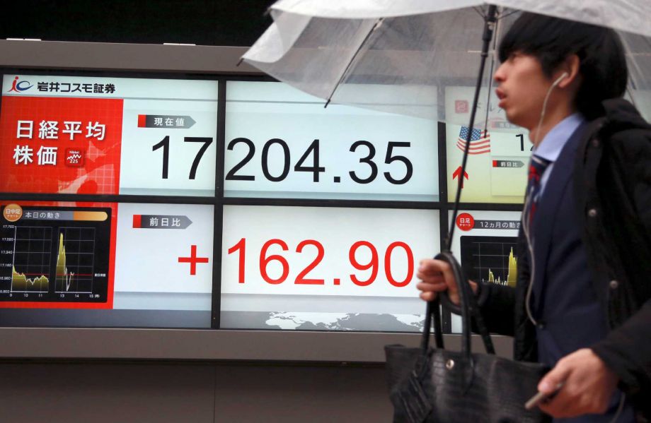 A man walks past an electronic stock board showing Japan's Nikkei 225 in Tokyo Friday Jan. 29 2016. Japanese stocks swung between gains and losses on Thursday and the yen dived after the country's central bank introduced a negative rate interest policy