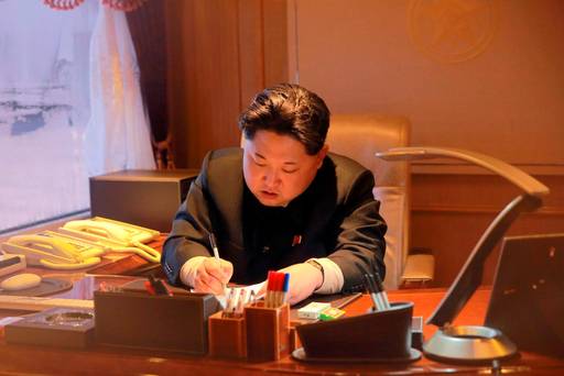 North Korean leader Kim Jong Un signs a document regarding a long range rocket launch in this undated