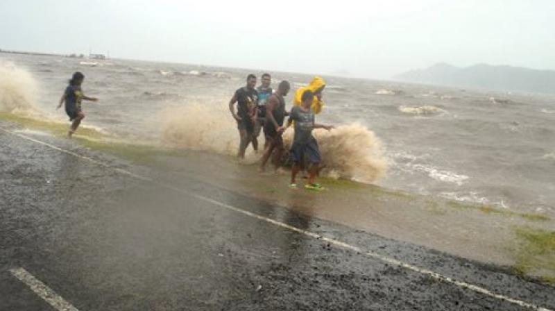 People are splashed by a wave whipped up by the encroaching cyclone Winston in Labasa Fiji