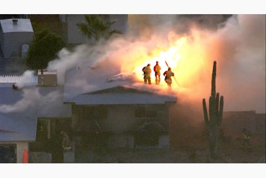 Firefighters went atop a Phoenix home to try extinguishing the fire on Tuesday. The home was also a scene of a shooting where a 26-year-old man shot and killed four family members. The gunman was fatally shot by police