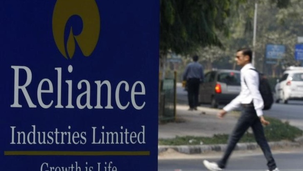 A man walks past a Reliance Industries Limited sign board installed on a road divider in Gandhinagar. | File  Reuters