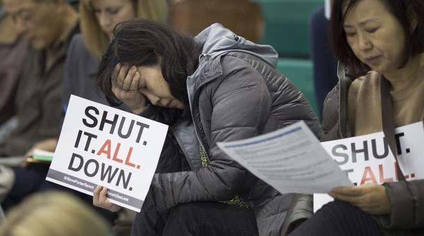 A woman holds a sign while attending a public hearing before the South Coast Air Quality Management District regarding a proposed order to stop a nearby massive natural gas leak