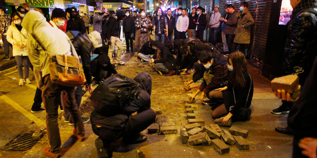 Protesters collect bricks from a pathway during clashes with police in Mong Kok district of Hong Kong