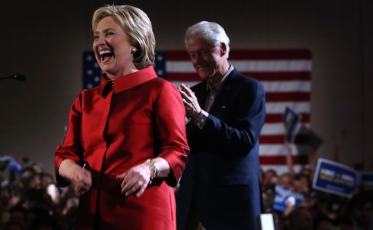 Hillary Clinton greeting supporters at a caucus day event as her husband former President Bill Clinton looks on at Caesars Palace in Las Vegas Nevada Feb. 20 2016