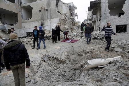 Residents inspect a crater at a site hit by what activists said were three consecutive air strikes carried out by the Russian air force in the rebel-controlled area of Maaret al Numan town in Idlib province Syria