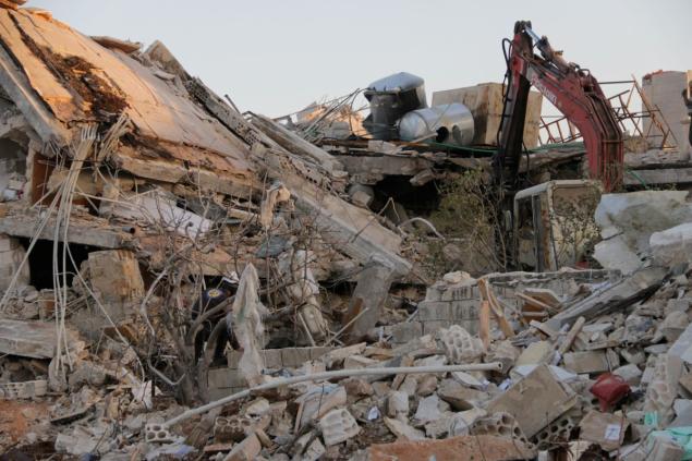 Rescue workers inspect the debris of a collapsed hospital to save victims after Russian forces allefgedly conducted airstrikes over residential areas in Syria