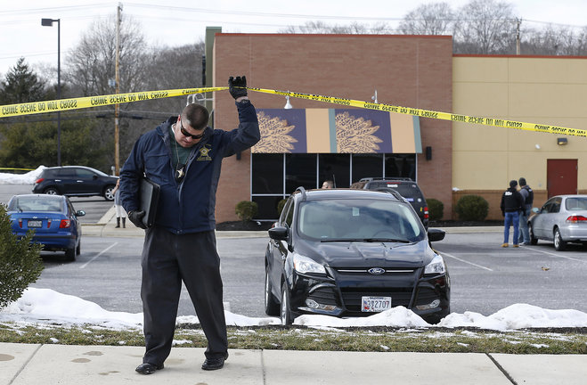 An investigator walks beneath a police tape line at the scene of a shooting at a shopping center in Abingdon Md. Wednesday Feb. 10 2016. A man opened fire inside a shopping center restaurant during lunchtime