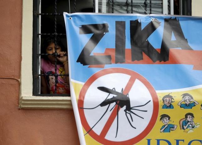 A woman looks on next to a banner as soldiers and municipal health workers take part in cleaning of the streets gardens and homes as part of the city's efforts to prevent the spread of the Zika virus vector the Aedes aegypti mosquito in Tegucigalpa Ho