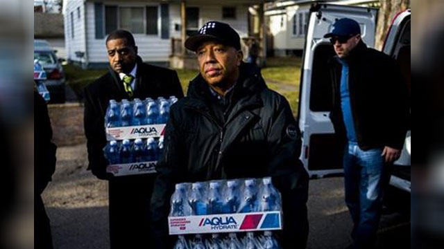 Def Jam co-founder Russell Simmons carries cases of bottled water as he hand delivers them to Flint resident Nakeyja Cade 24 a mother of three as he makes stops throughout Flint listening to their personal stories to understand the issue on the ground