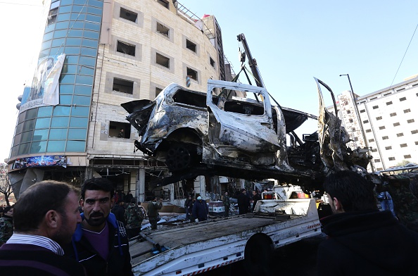 The wreckage of a vehicle is being loaded on a truck as Syrian pro-government forces and residents gather at the site of suicide bombings in the area of a revered Shiite shrine in the town of Sayyida Zeinab on the outskirts of the capital Damascus on Ja