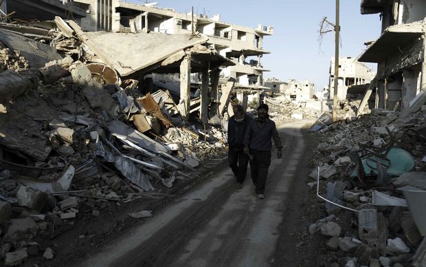 Syrian men walk along a street damaged by shelling in the neighbourhood of Jobar on the eastern outskirts of the capital Damascus