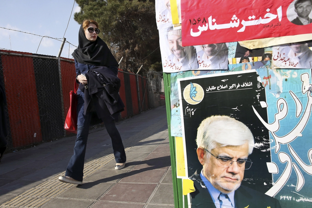 An Iranian woman walks past electoral posters of candidates of parliamentary elections in a sidewalk in Vanak square in northern Tehran Iran Thursday Feb. 25 2016. Iran