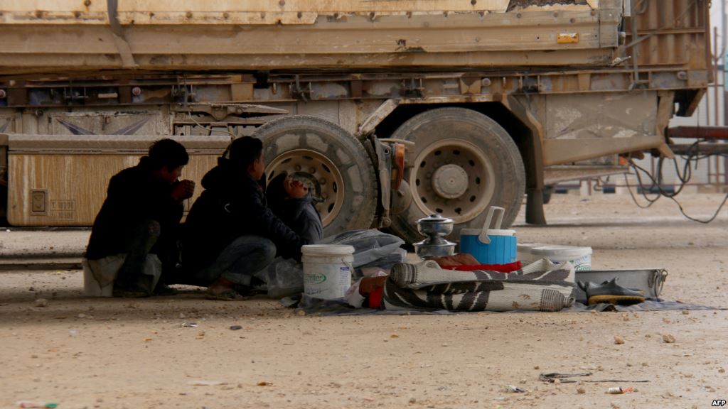 Displaced Syrians fleeing areas in the northern embattled province of Aleppo sit under a truck at the Bab al Salama camp set up outside the Syrian city of Azaz on Syria's northern border with Turkey Feb. 12 2016