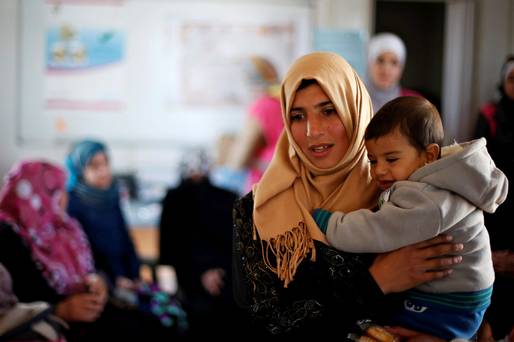 Syrian refugee Burooq Al Zubi 21 carries her nine-month-old son Fares as she speaks to other women about her experience as a breast cancer patient during an awareness seminar at Al Zaatari refugee camp in the Jordanian city of Mafraq near the border