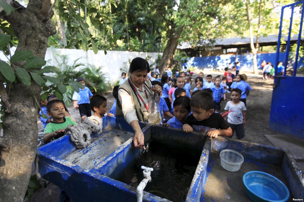 Health promoter Marielos Sosa deposits fishes in a water tank at a local school for a mosquito control project at San Diego village in La Libertad El Salvador Feb. 1 2016. Sosa and a group of young volunteers developed a project which they say uses Sam