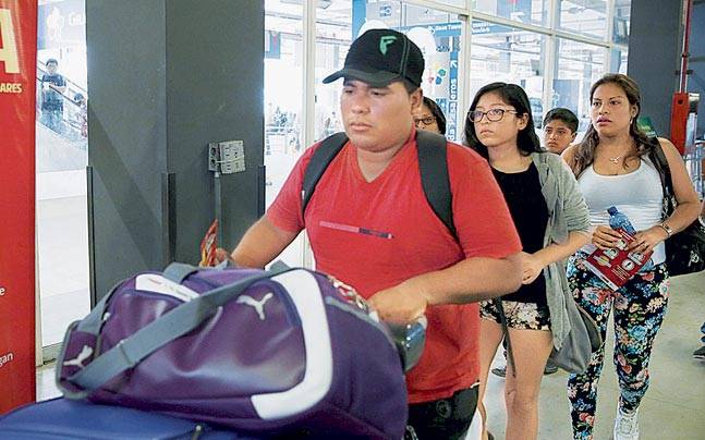 Travellers walk past a poster with information about the Zika virus