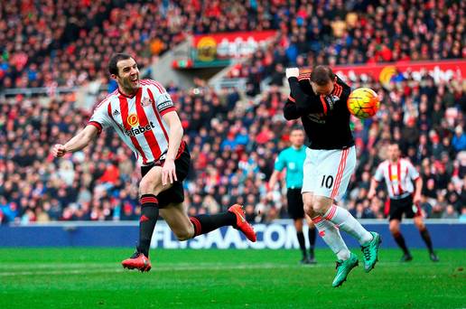 Wayne Rooney ducks for cover as John O’Shea gets in a header at the Stadium of Light