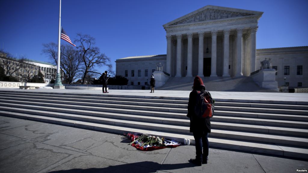 FILE- Flowers are seen as a woman stands in front of the Supreme Court building in Washington D.C. after the death of U.S. Supreme Court Justice Antonin Scalia Feb. 14 2016. Many Senate Republicans say Obama a Democrat should not nominate someone