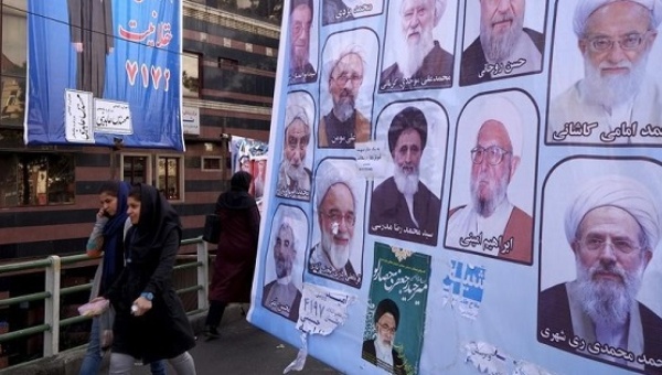 Women walk past electoral posters for the upcoming elections in central Tehran