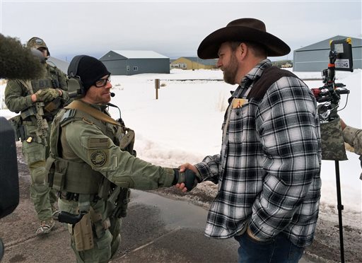 Ammon Bundy right shakes hand with a federal agent guarding the gate at the Burns Municipal Airport in Oregon on Friday Jan. 22 2016. Bundy is the leader of an armed group occupying a national wildlife refuge to protest federal land policies. (AP Phot