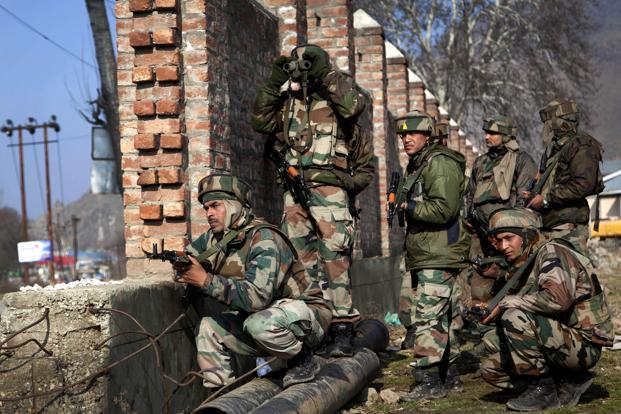 Soldiers take cover behind a wall during a gunbattle with militants on the outskirts of Srinagar on Sunday