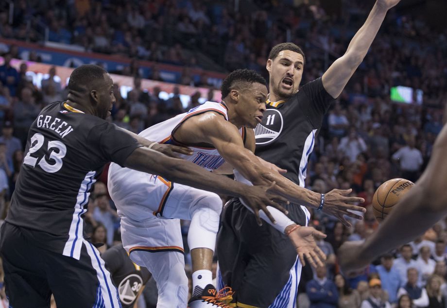 Russell Westbrook #0 of the Oklahoma City Thunder is forced to pass the ball after Draymond Green #23 and Klay Thompson #11 of the Golden State Warriors trap him during the overtime period of a NBA game at the Chesapeake Energy Arena