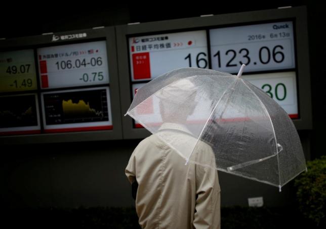 A man looks at an electronic board showing the recent exchange rate between Japanese yen against the U.S. dollar and Japan's Nikkei average outside a brokerage in Tokyo Japan