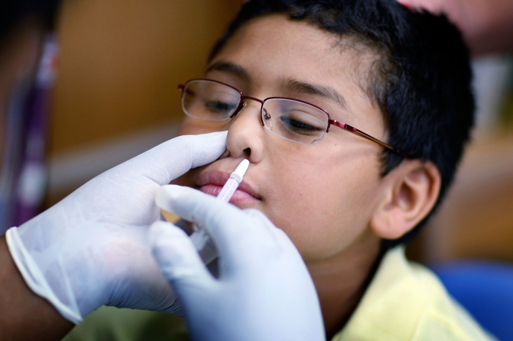 MIAMI- OCTOBER 19 Chris Diaz,8 receives a H1N1 nasal flu spray vaccine from nurse Shajaira Powell Bailey at the Broadmoor Elementary school