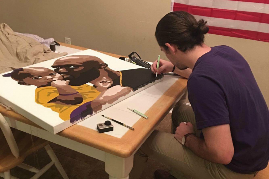 LSU art student Michael Anderson signs the piece he painted for RB Leonard Fournette and his daughter Lyric