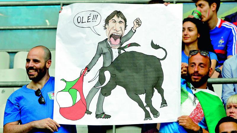 An Italian supporter holds a drawing showing Italy coach Antonio Conte as a bullfighter during the match against Spain at the Stade de France in Paris on Monday