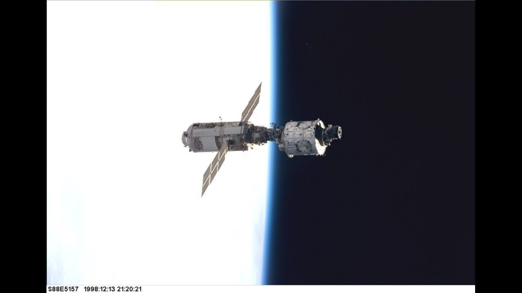 The Zarya control module on the left with the solar panels floats above Earth with its newly attached Unity module after the first assembly sequence in December 1998