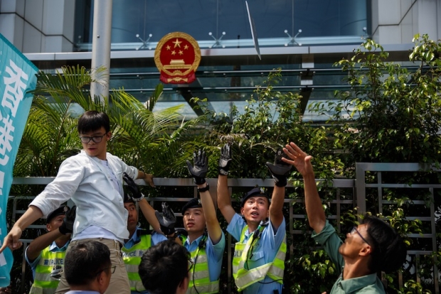 A pro-democracy group Demosisto member throws a placard towards the Chinese Liaison office during a protest in Hong Kong