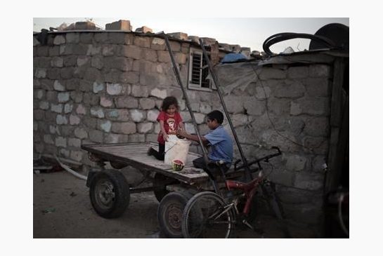 Palestinian children prepare food for a horse as they sit on a cart next to their house in El Zohor slum on the outskirts of Khan Younis refugee camp southern Gaza Strip. The expansion of the El Zohor slum where bare