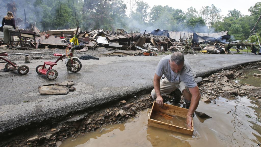 Mark Lester cleans out a box with creek water as he cleans up from severe flooding in White Sulphur Springs W. Va