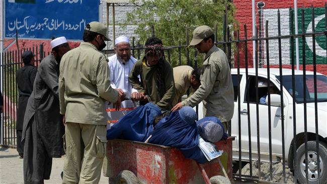 Pakistani border security personnel search an Afghan family entering Pakistan after crossing the Torkham Border