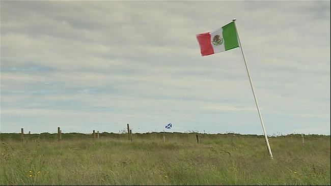 The Mexican flag foreground and the Scottish flag blow in the wind on land near Turnberry golf course in Scotland owned by David Milne one of Donald Trump's long-standing opponents in Scotland on this image taken from video Wednesday