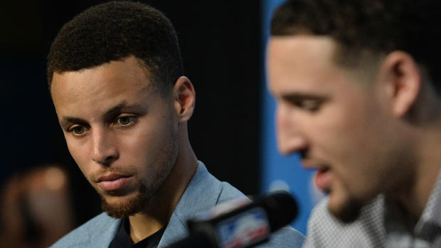 Stephen Curry looks on while Klay Thompson answers a question