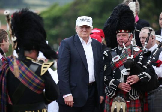 Donald Trump poses with a bagpiper as he arrives at his revamped Trump Turnberry golf course in Turnberry Scotland