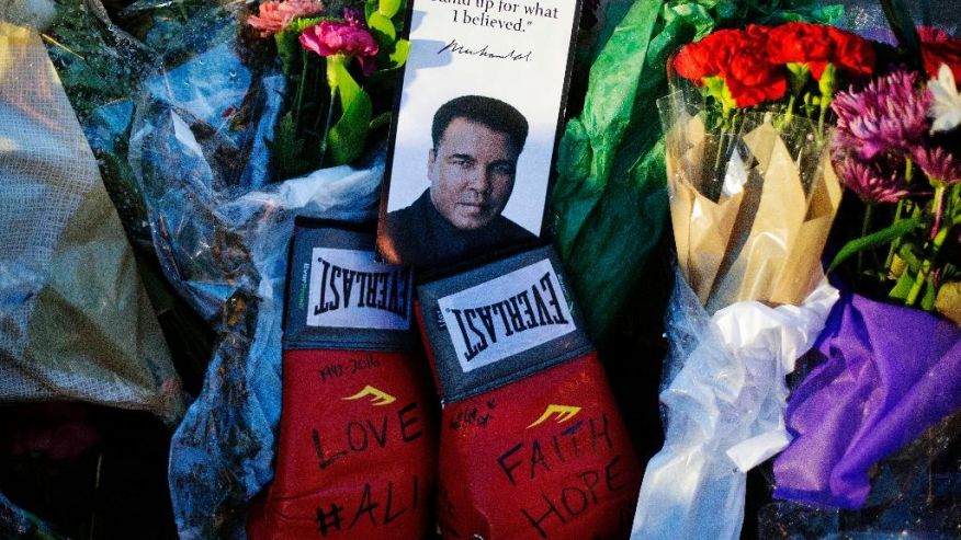 Boxing gloves and a message sit among flowers at a makeshift memorial to Muhammad Ali at the Muhammad Ali Center Saturday