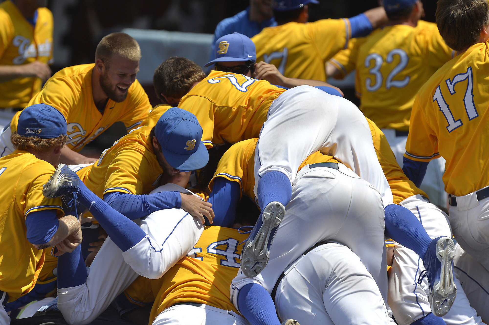 Members of UC Santa Barbara pile onto teammate Sam Cohen following his walkoff grand slam to win an NCAA college baseball tournament super regional game against Louisville Sunday