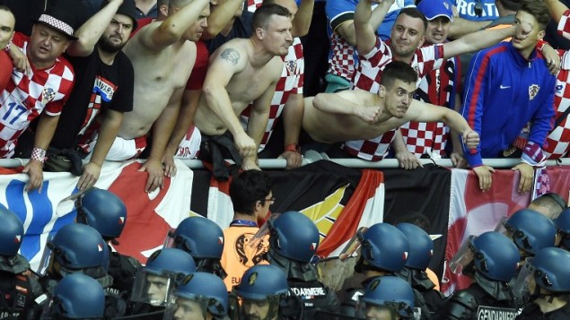 Croatia fans react as French riot police look up at them after flares were thrown onto the pitch during the Euro 2016 group D football match between Czech Republic and Croatia at the Geoffroy Guichard stadium in Saint Etienne