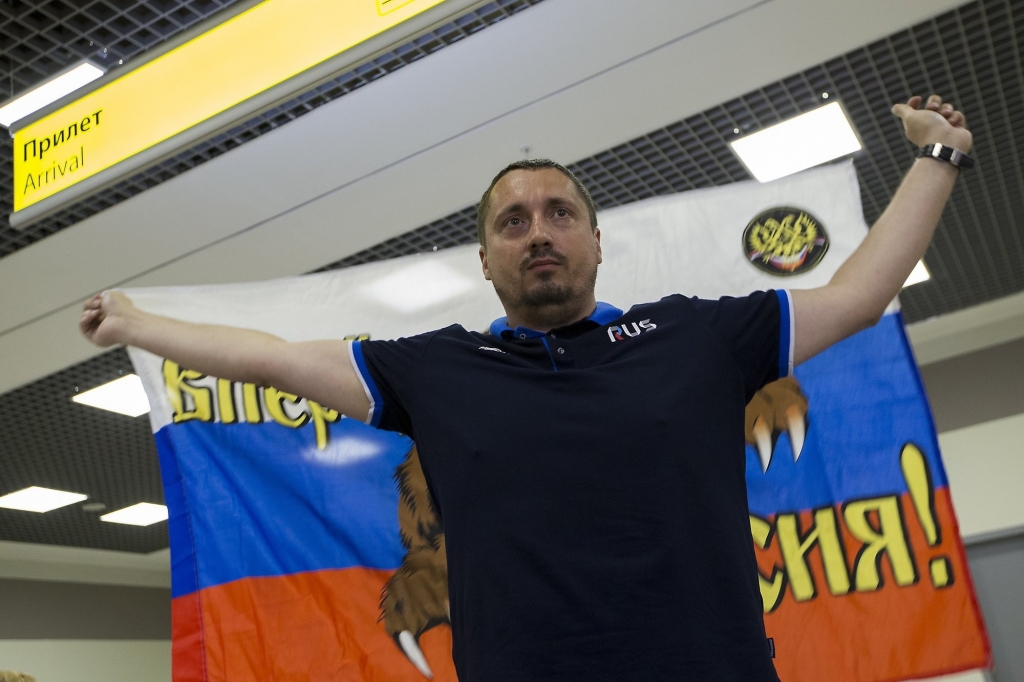 Alexander Shprygin the leader of a Russian fan group holds a Russian flag depicting a bear and reading Russia Forward while speaking to the media as a group of soccer fans deported from France arrived in Moscow Russia Saturday