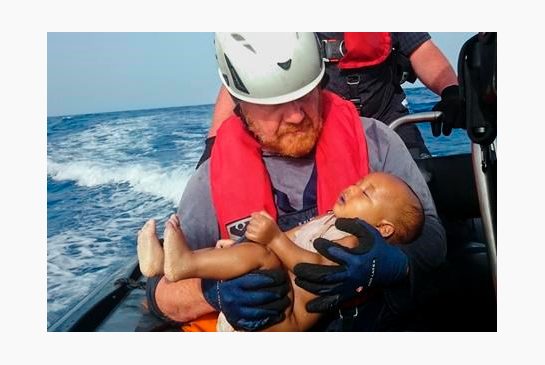 Sea Watch humanitarian organization crew member holds a drowned migrant baby during a rescue operation off the coasts of Libya. Survivor accounts have pushed to more than 700 the number of migrants feared