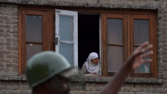 A Kashmiri Muslim woman looks out from a window of a home during a curfew in Srinagar