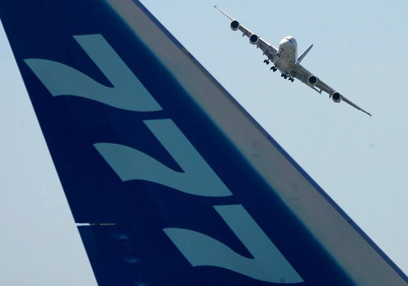 The tail of a Boeing 777 plane is seen as an Airbus A380 the world's biggest airliner flies in the background at the Paris Air Show in Le Bourget near Paris